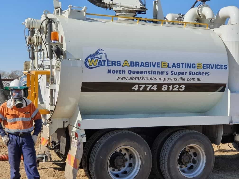 A Man is Standing Next to a Waters Abrasive Blasting Services Truck — Waters Abrasive Blasting Services In Shaw, QLD