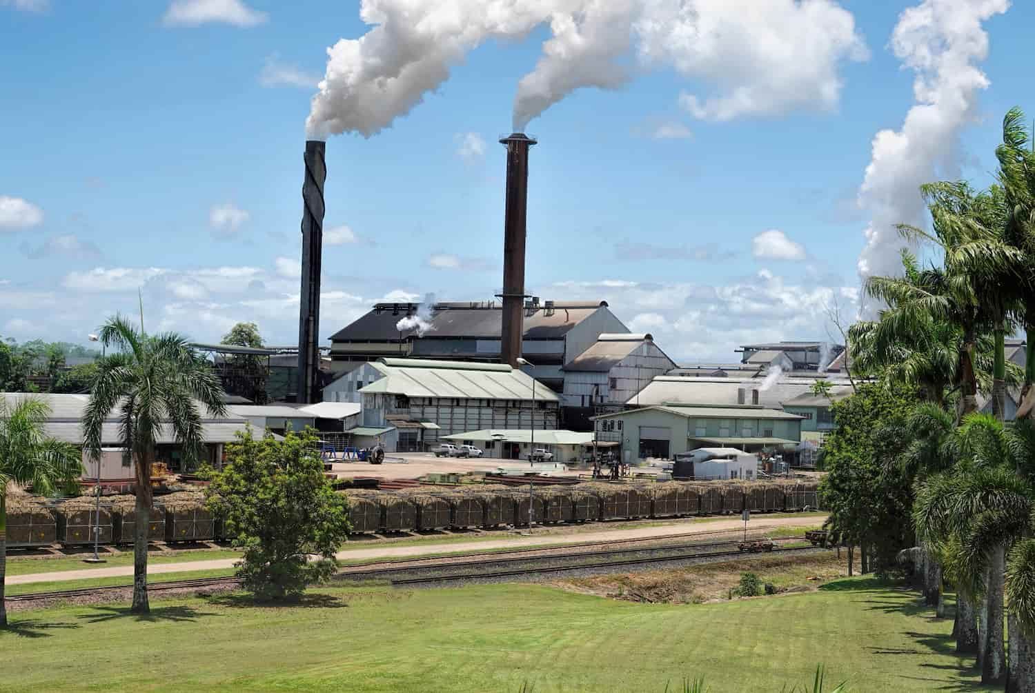 A Factory With Smoke Coming Out of the Chimneys — Waters Abrasive Blasting Services In Shaw, QLD