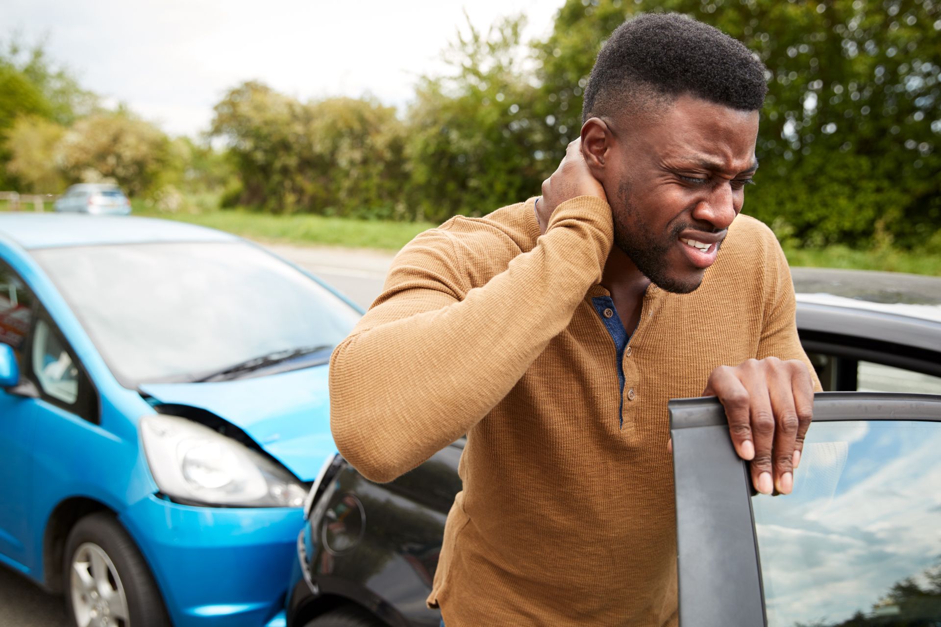 A man is holding his neck after a car accident.