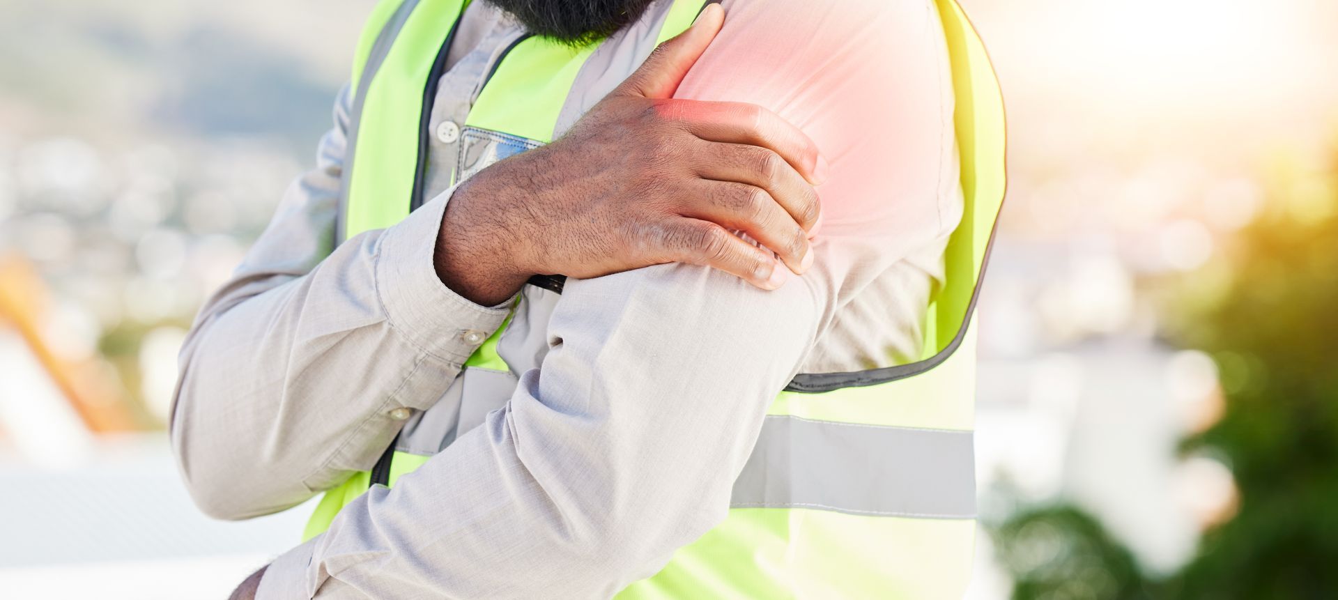 A construction worker is holding his shoulder in pain.