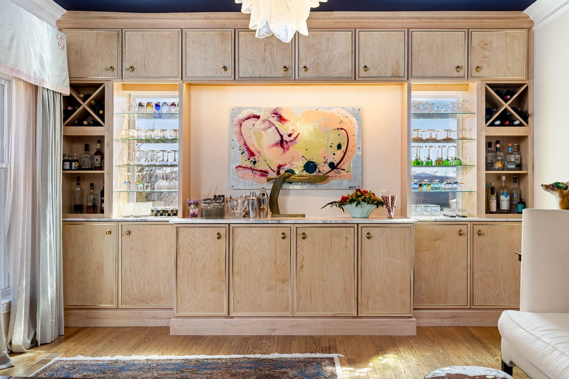 Built-in bar with light wood cabinets, wine racks, and colorful artwork.