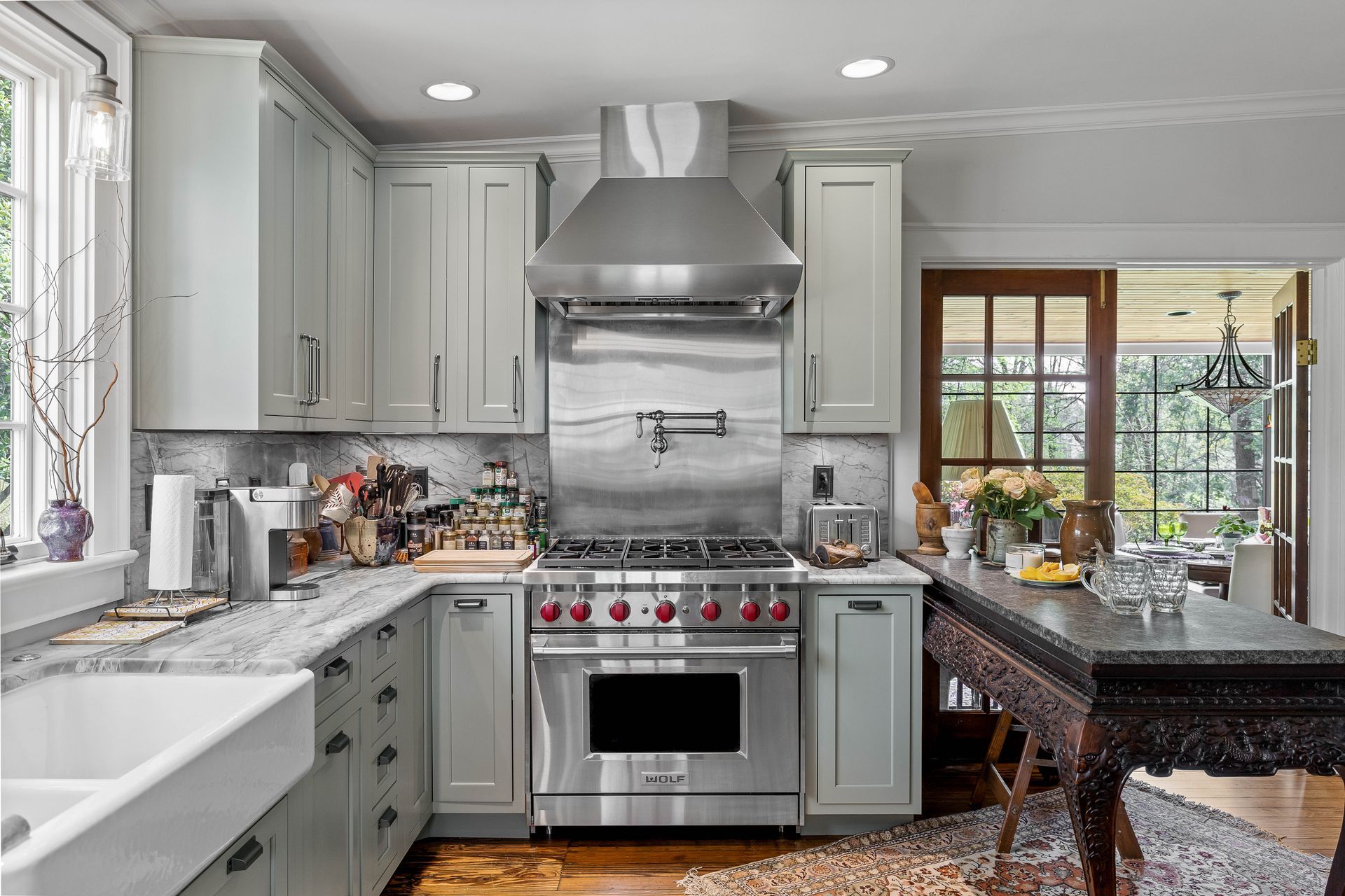 Light blue kitchen with stainless steel appliances, an island, and a view of a porch.