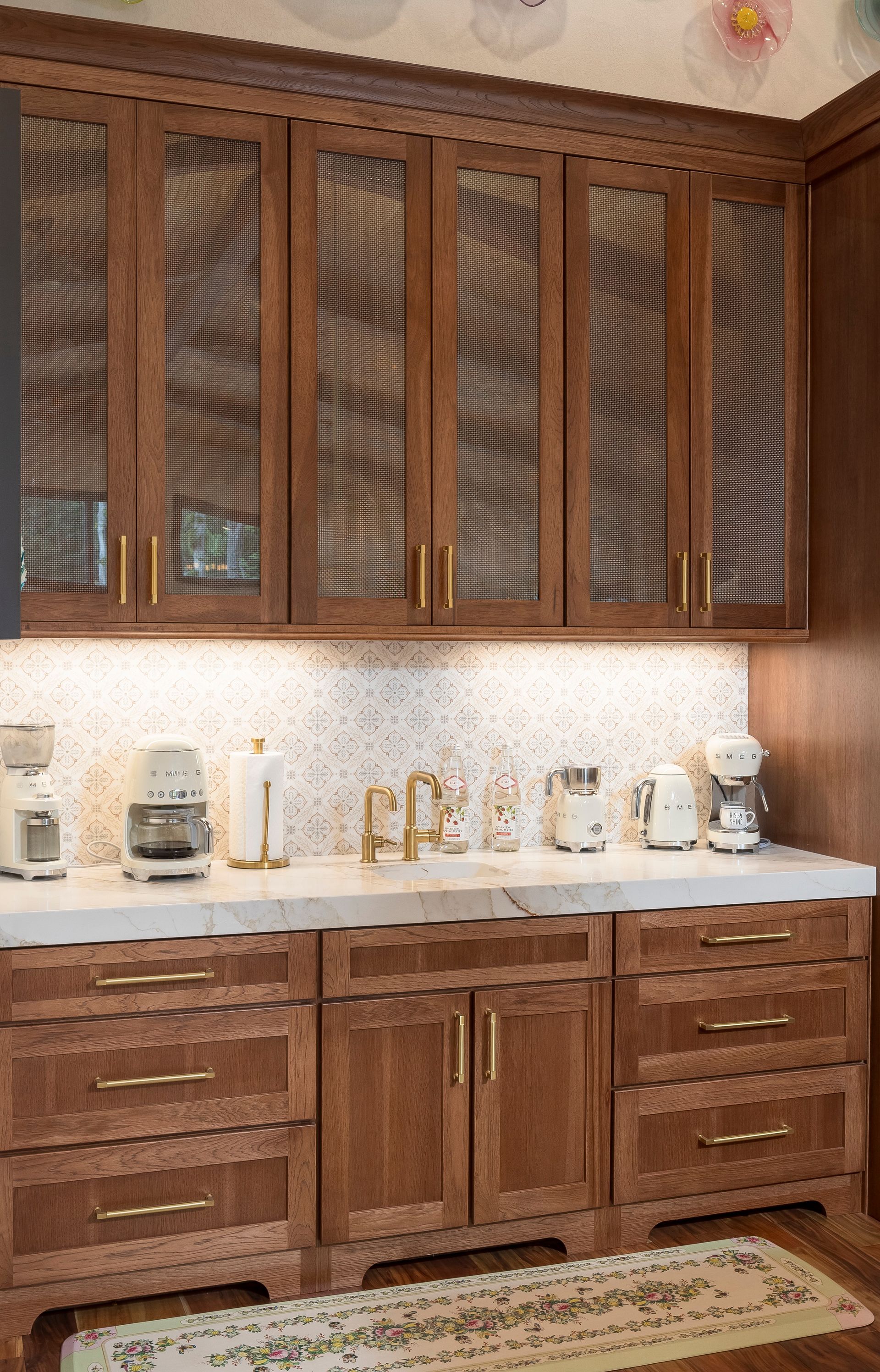 Wooden kitchen cabinets with gold hardware, countertop, and coffee makers.