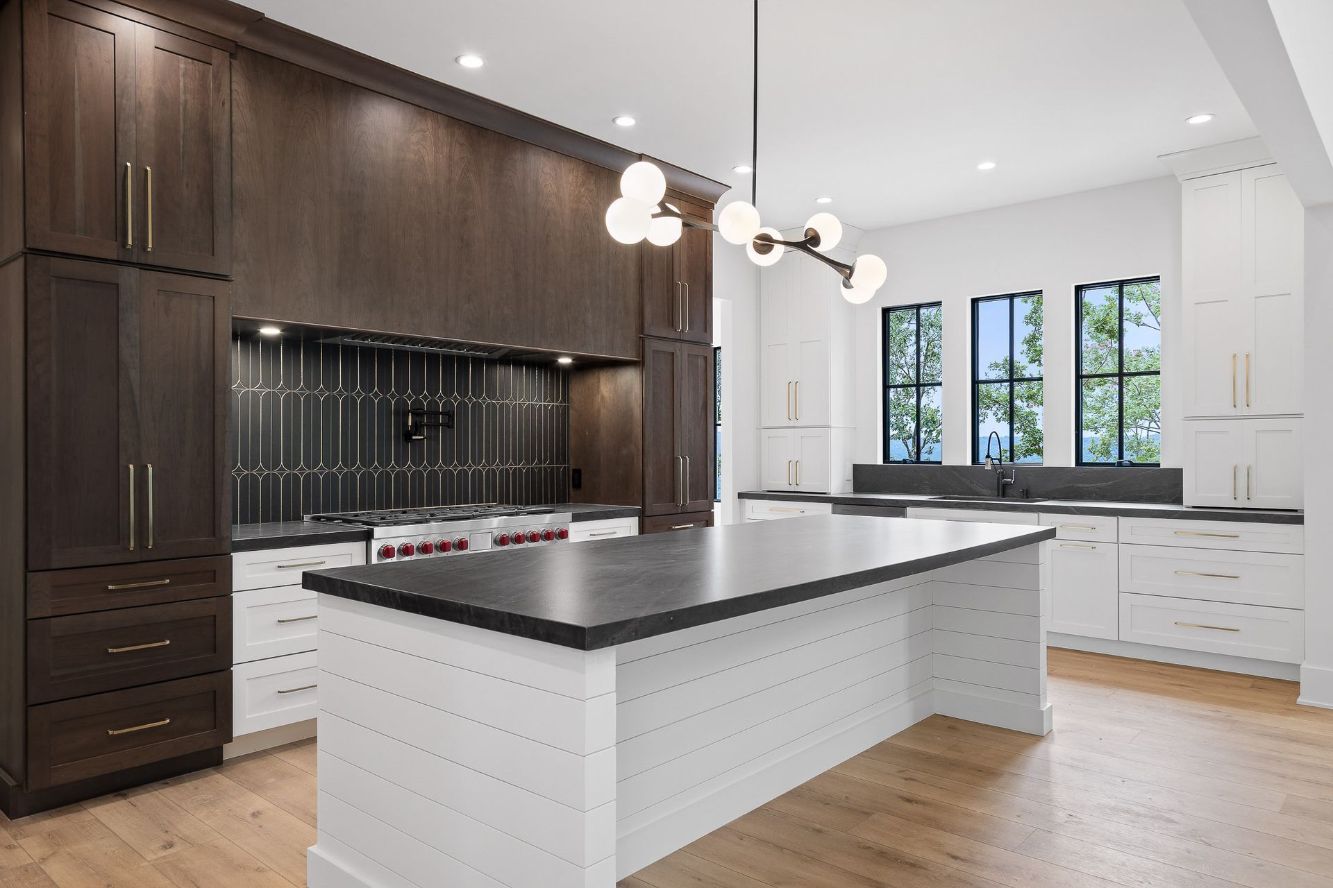 Modern kitchen with dark wood cabinets, white island and countertops, and a light fixture.