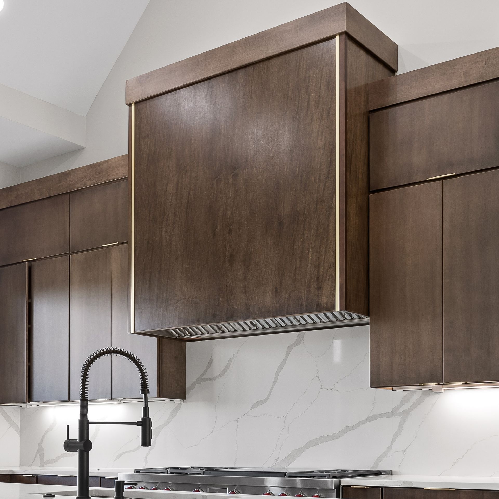 Modern kitchen with dark wood cabinets, marble backsplash, and black faucet over a sink