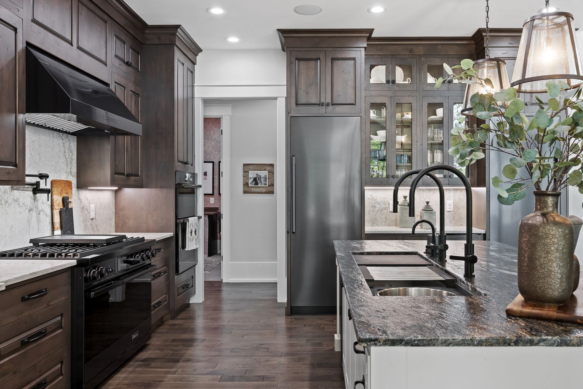 Kitchen with dark brown cabinets, stainless steel appliances, granite countertops, and hardwood floors.