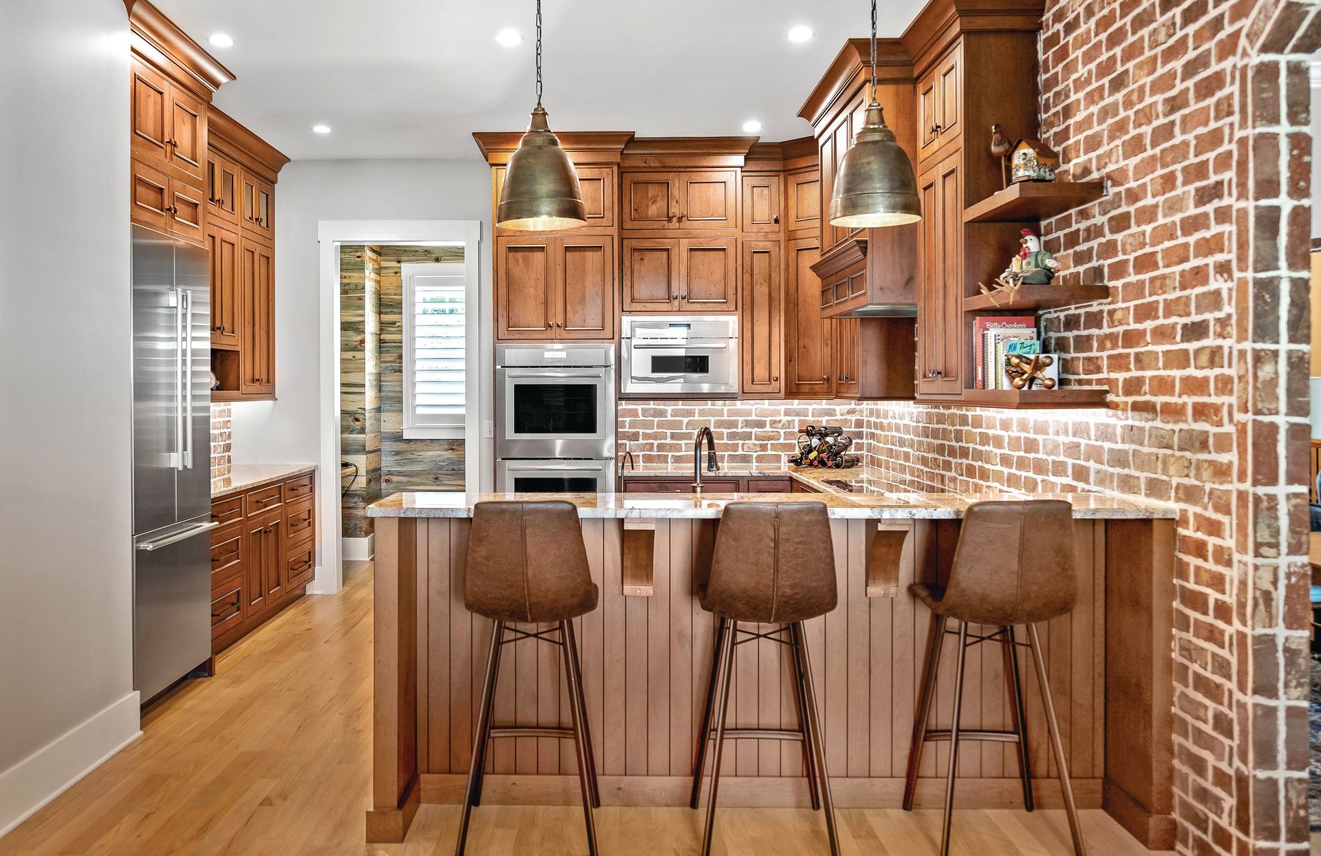 Elegant kitchen with wood cabinets, brick wall, and a breakfast bar with stools.