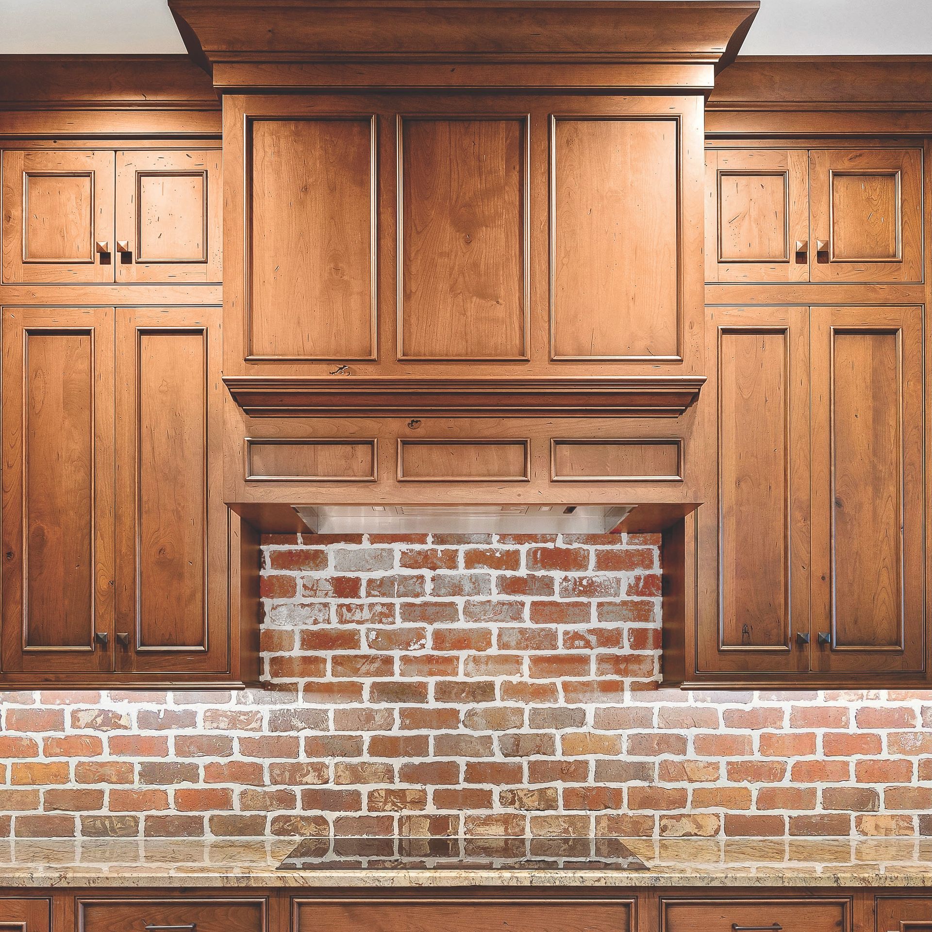 Wood-paneled built-in cabinets and mantel above a brick hearth, with exposed brick backsplash.