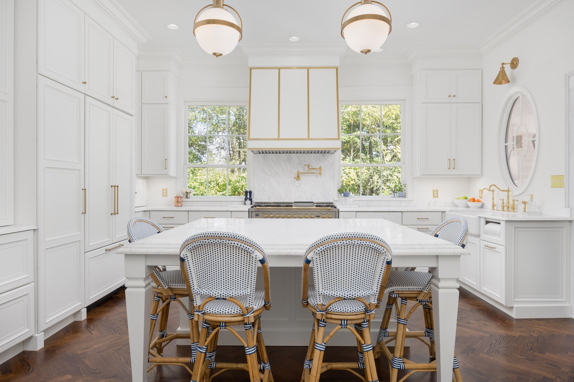 White kitchen with island seating, brass accents, and two globe pendant lights.