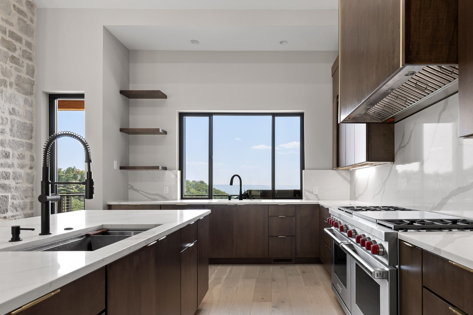 Modern kitchen with dark wood cabinets, white countertops, and a large window.
