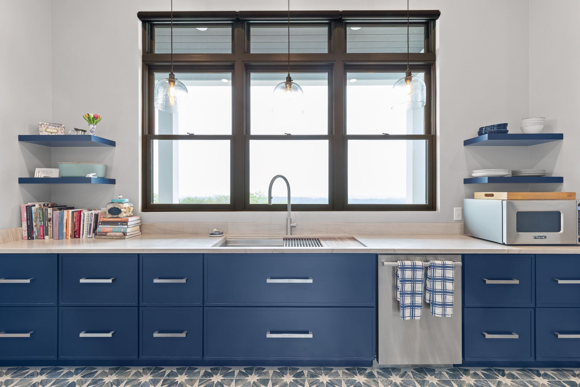 Kitchen with navy blue cabinets, light countertops, and a large window.