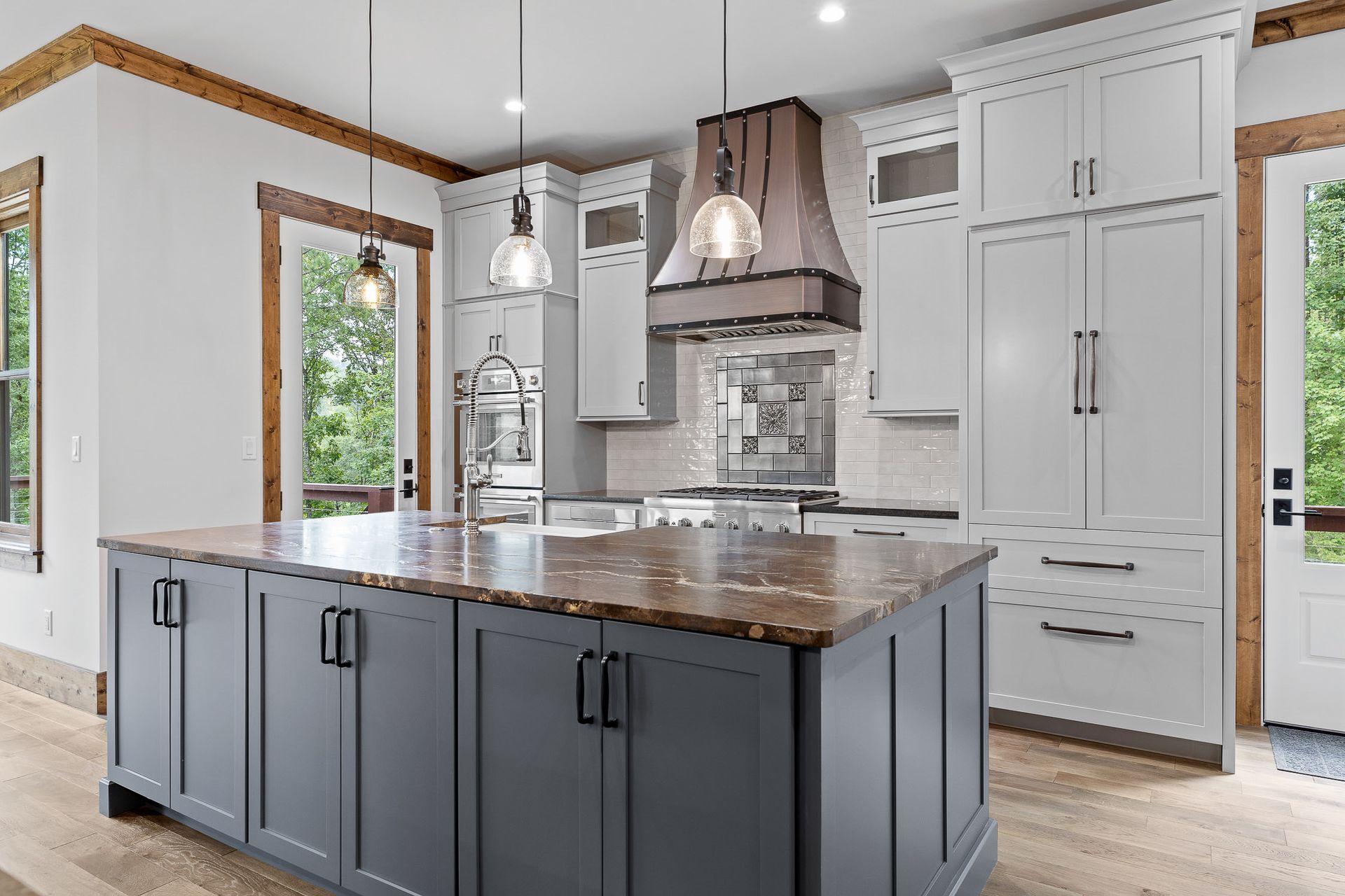 Modern kitchen with blue island, white cabinets, and brown range hood.