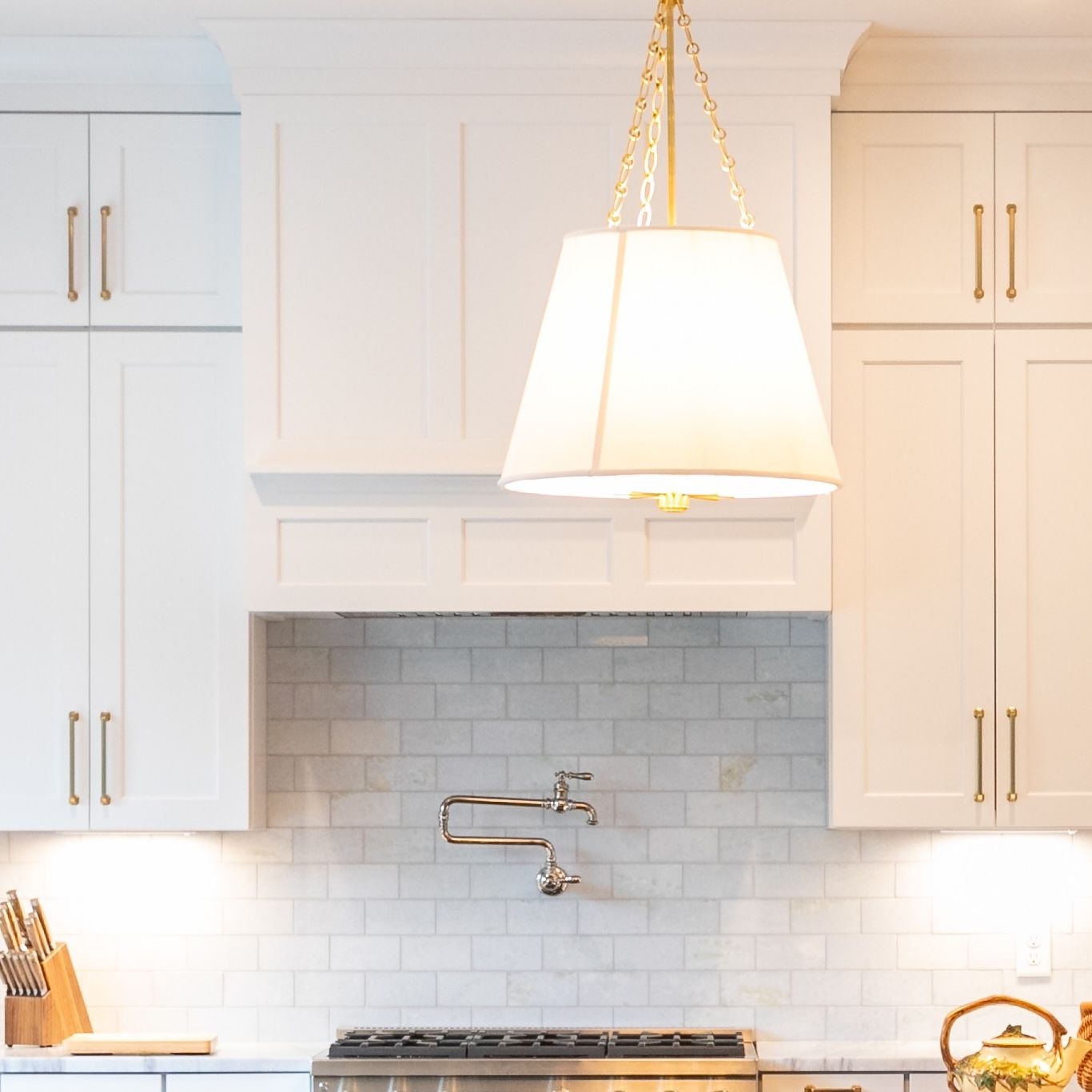 Bright white kitchen with subway tile backsplash, gas stove, and hanging pendant light