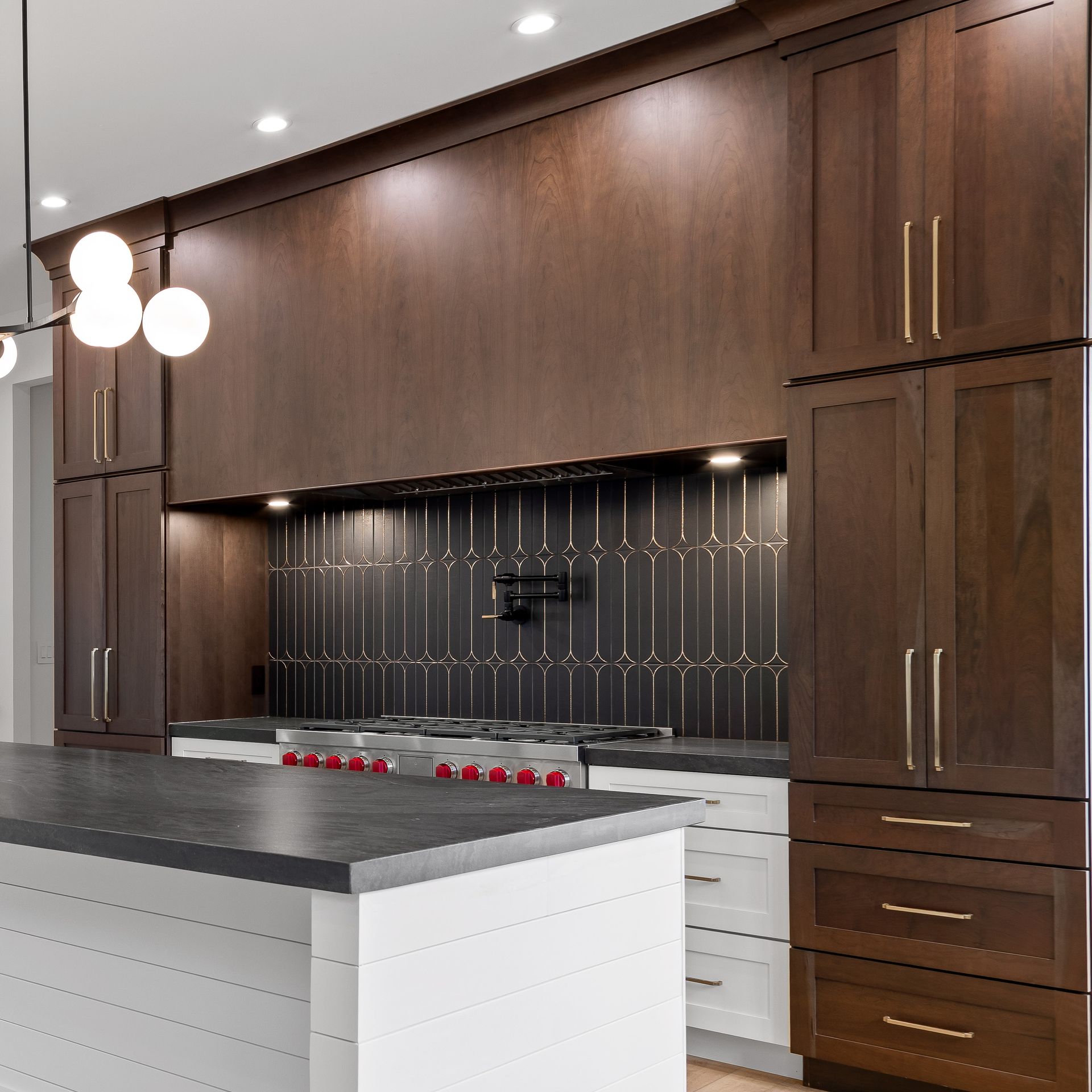 Modern kitchen with dark wood cabinets, black backsplash, and a large island with white drawers.