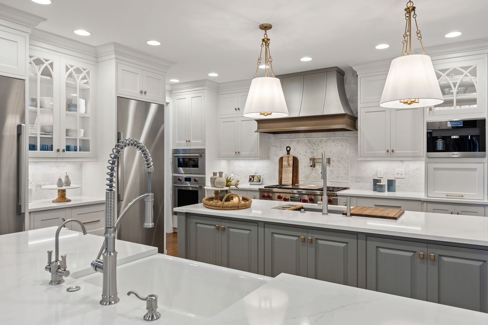 Elegant, spacious kitchen with white and gray cabinets, stainless steel appliances, and a large island.