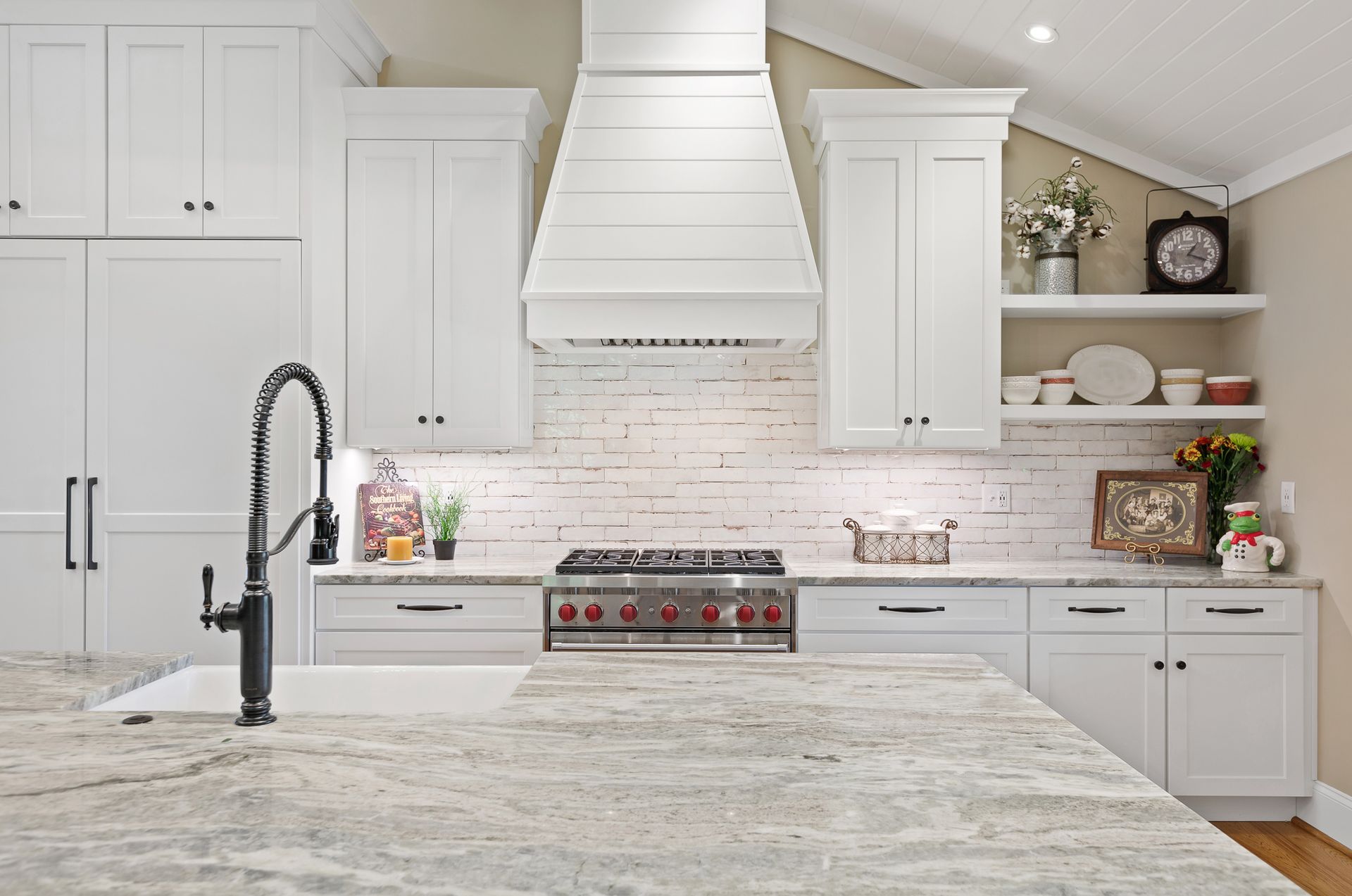 White kitchen with a large island, range, and range hood; granite countertops.