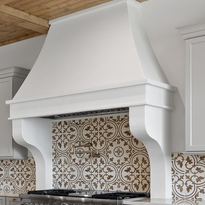 White kitchen range hood above patterned tile backsplash and stovetop