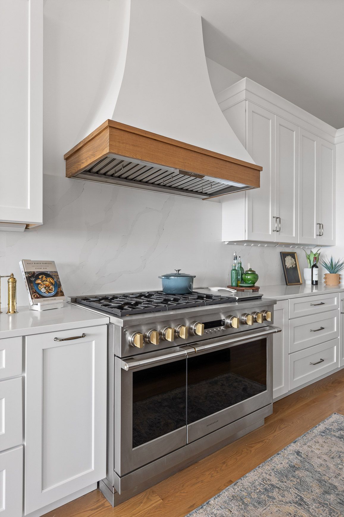Modern kitchen with stainless steel range, white cabinets, and wooden range hood.