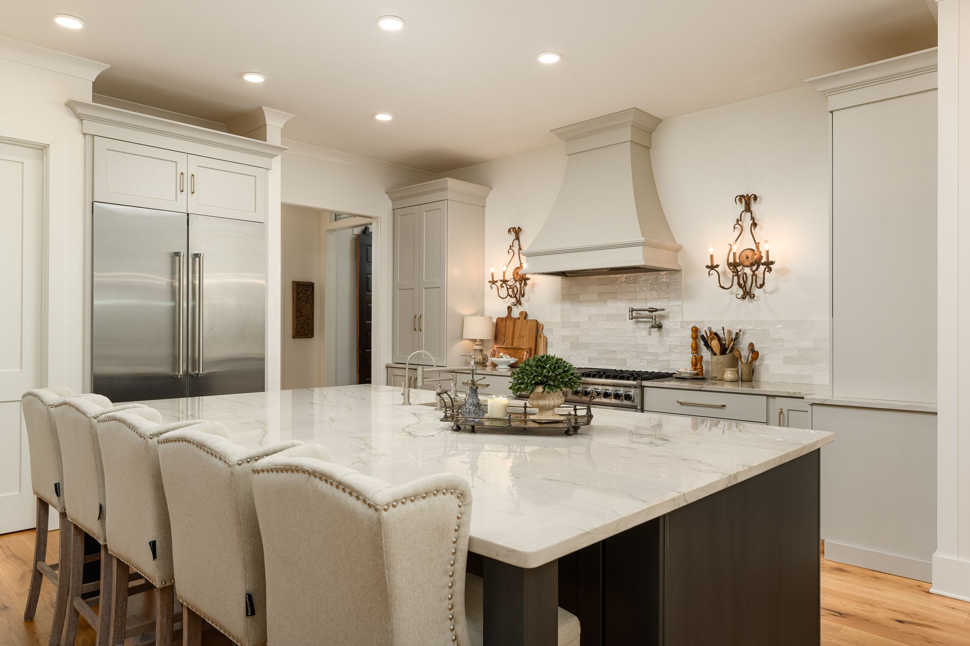 Modern kitchen with white cabinets, large island with seating, and stainless steel appliances.