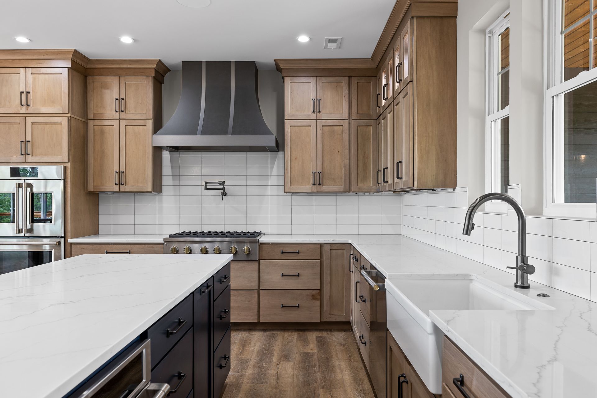 Modern kitchen with light wood cabinets, white countertops, stainless steel appliances, and a dark blue island.
