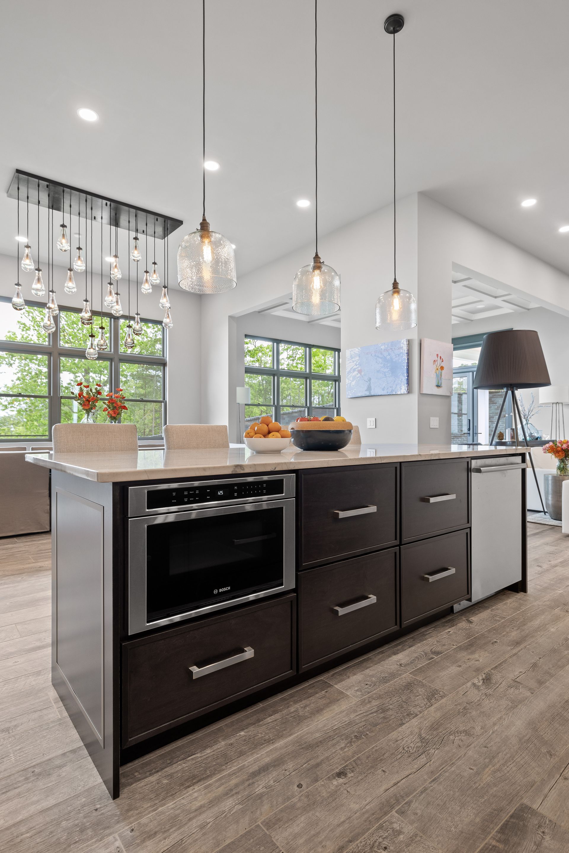 Modern kitchen island with oven, drawers, and dishwasher, with pendant lights overhead.