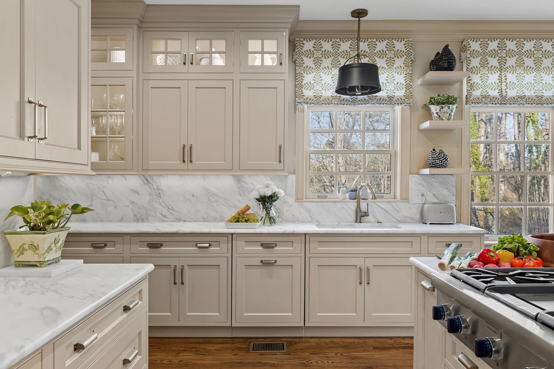 A kitchen with white cabinets , a stove , a sink , and a window.