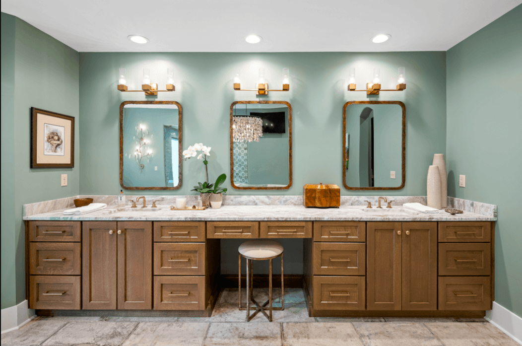 A bathroom with two sinks , two mirrors , and a stool.