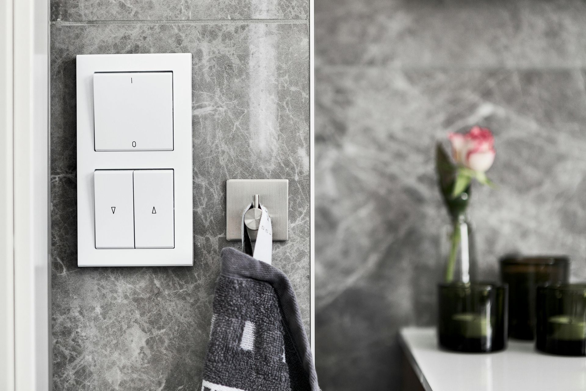A towel is hanging on a hook in a bathroom next to a light switch.