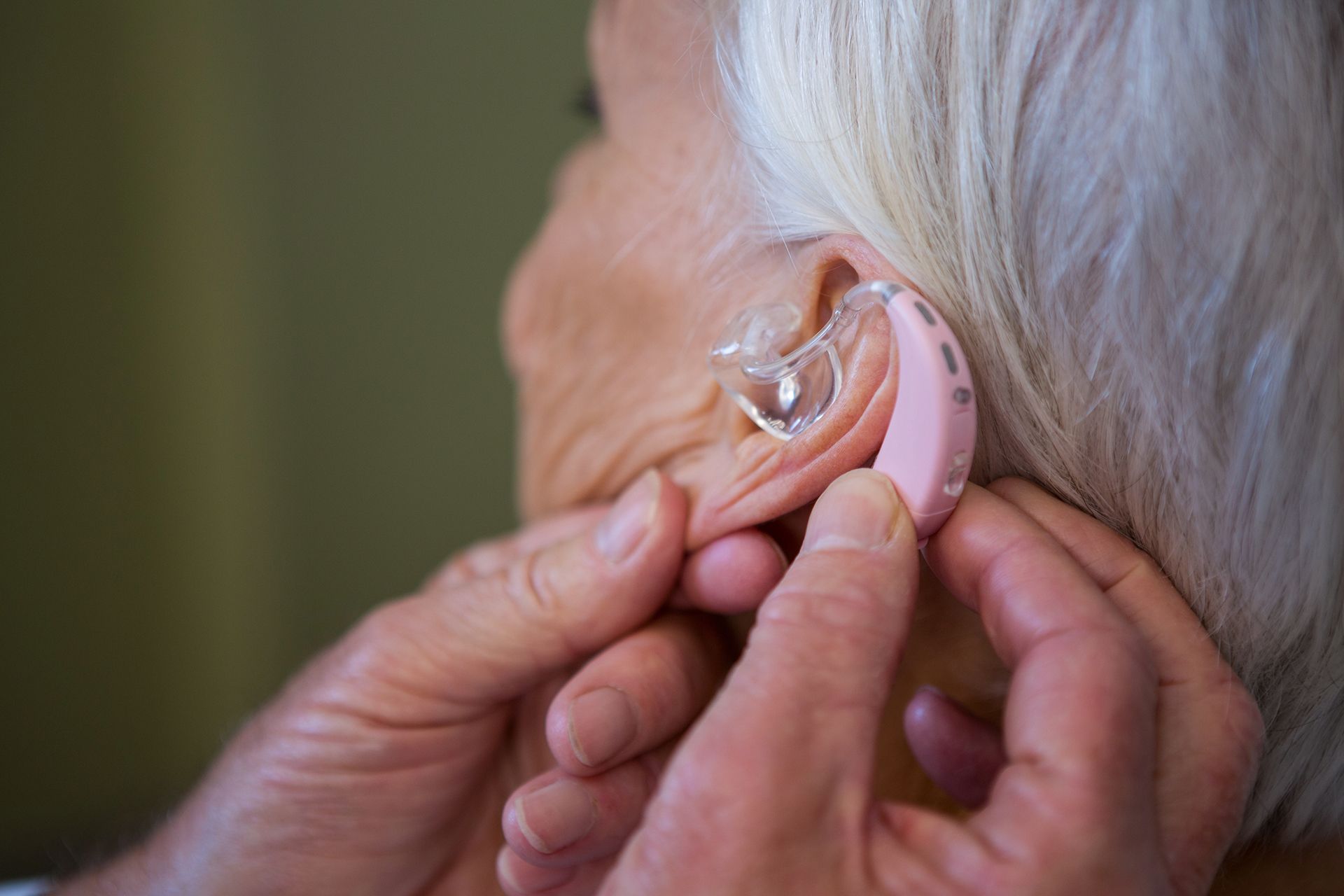Putting a New Hearing Aid on Senior Woman's Ear