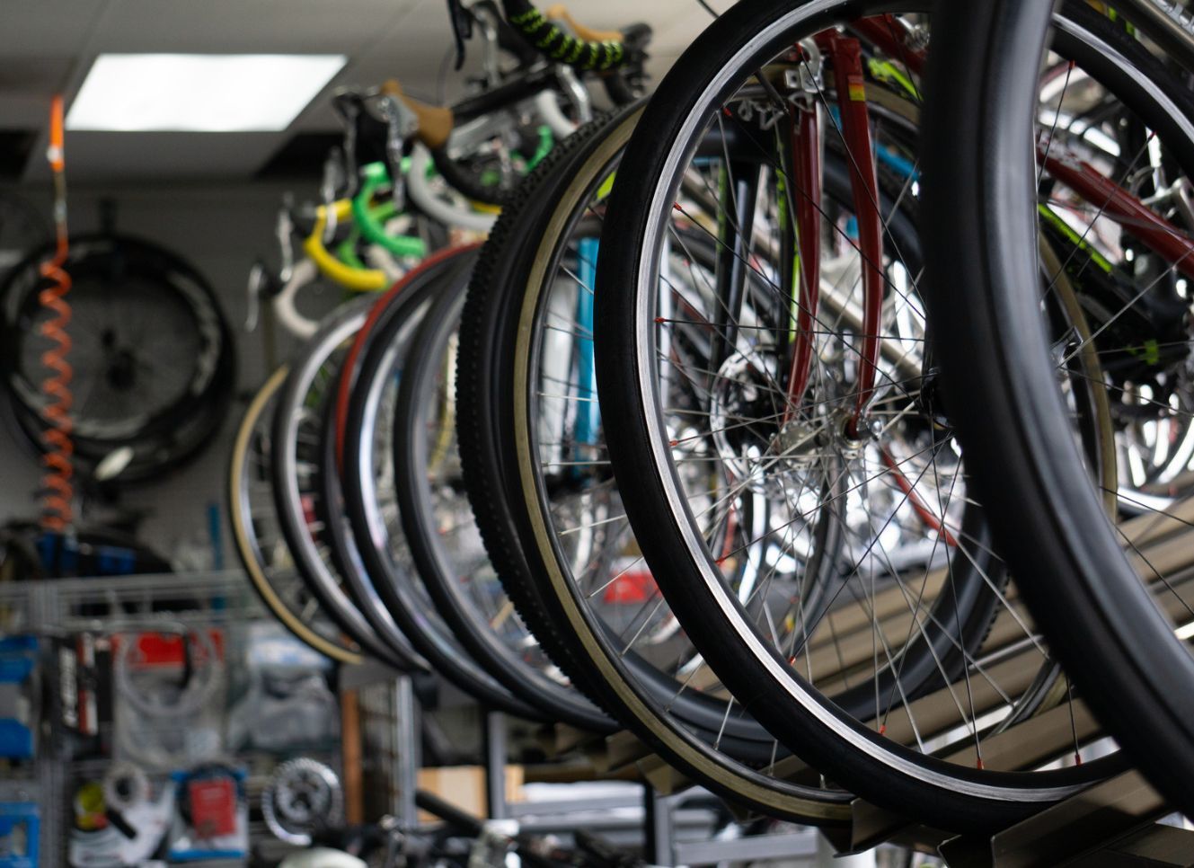 File di biciclette appese in un negozio di bici, con ruote e telai in primo piano