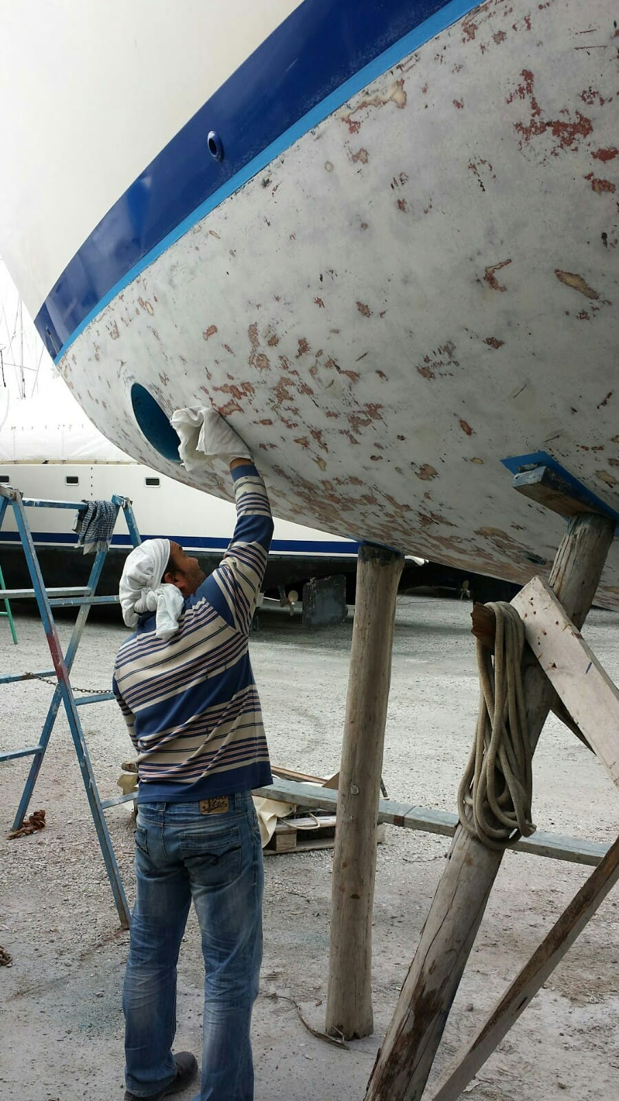 A Man Is Working On The Side Of A Boat — Baran Yachting in Sunshine Coast, QLD