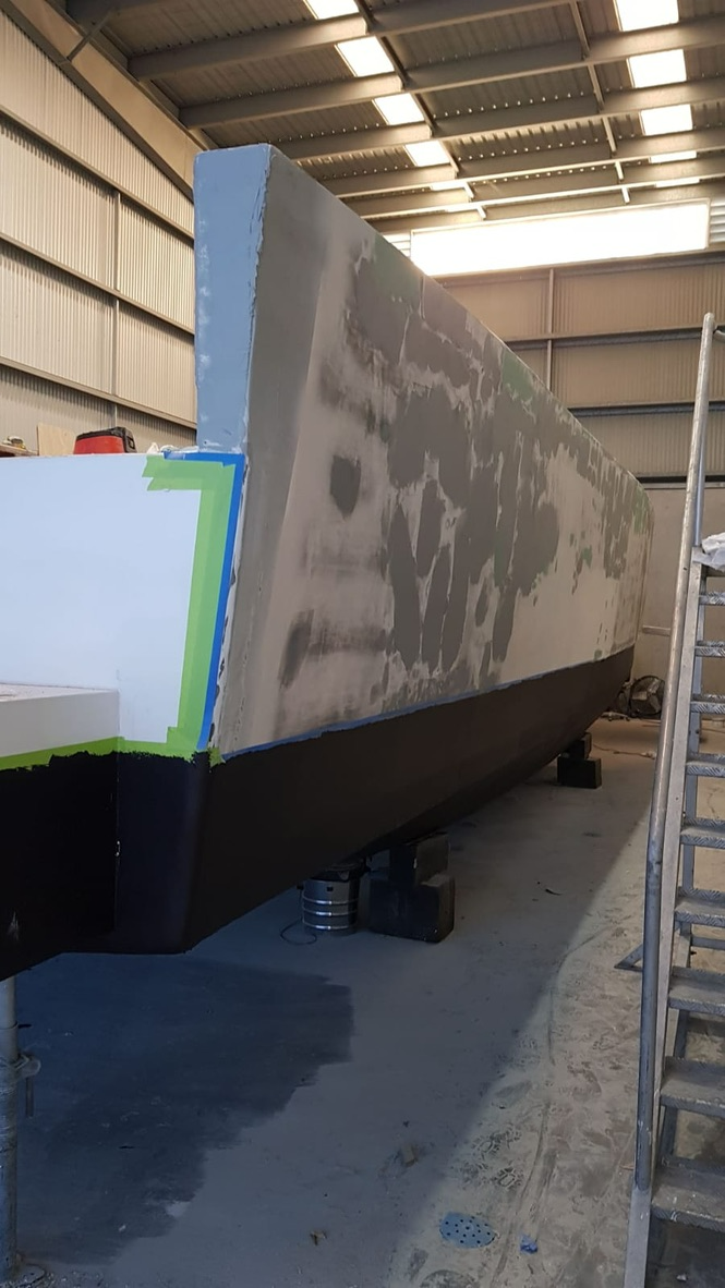 A Large Boat Is Being Painted In A Warehouse — Baran Yachting in Sunshine Coast, QLD