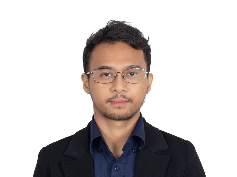 Headshot of a person in glasses and a dark blazer against a white background