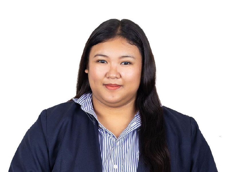 Portrait of a smiling person in a navy blazer and striped shirt against a white background