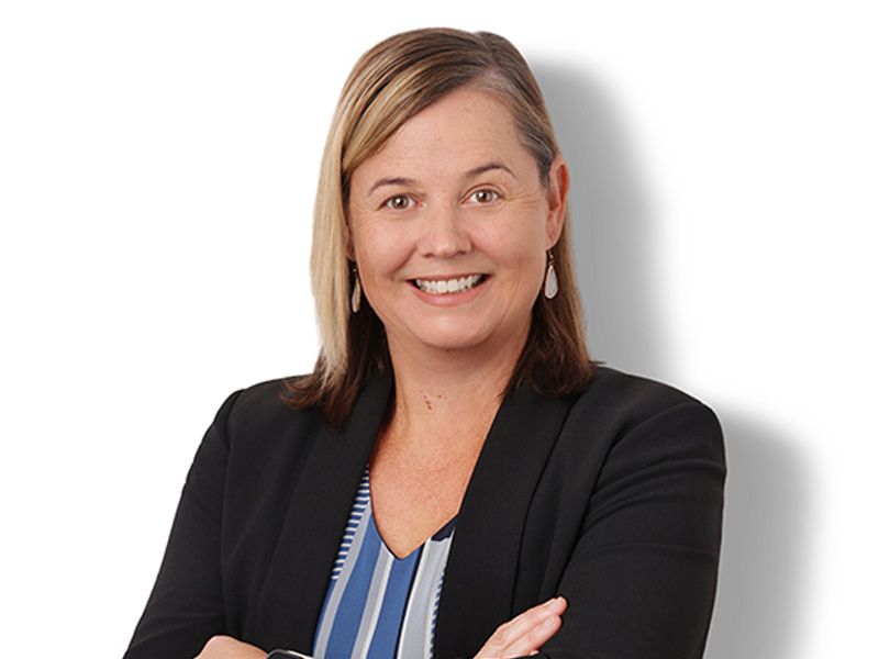 Smiling professional in black blazer with arms crossed on a white background