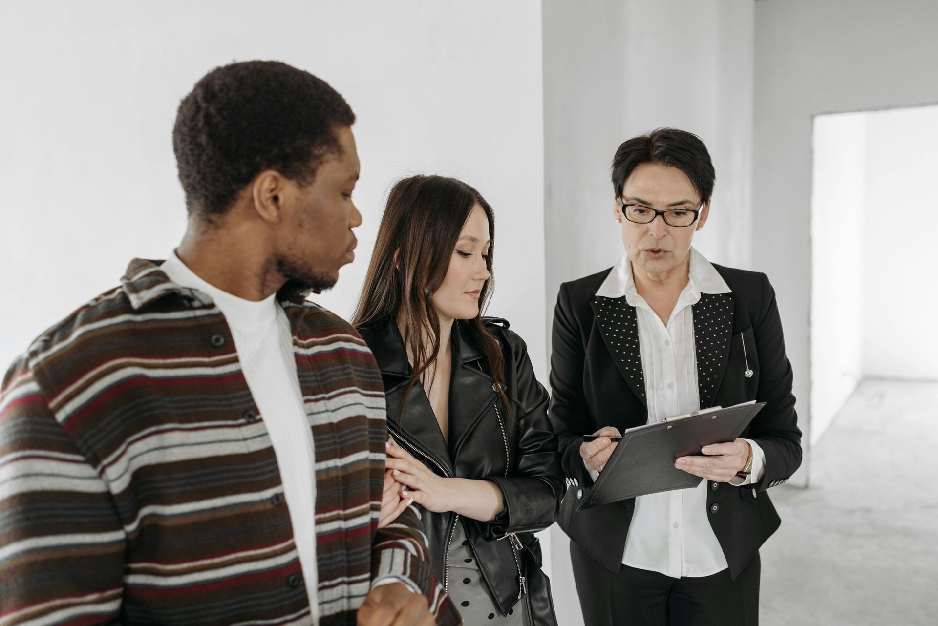 Three colleagues talking in a bright office, one holding a clipboard and papers