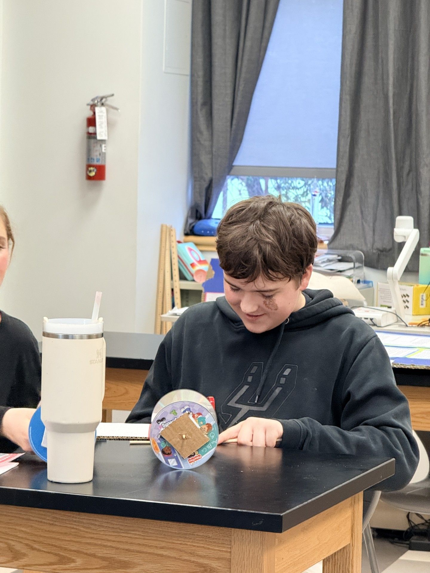 Boy in a science lab is building a wheel axle out of plastic.