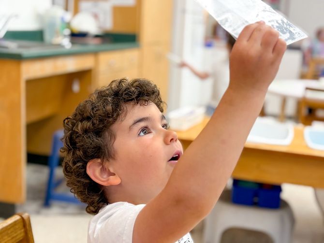 Young boy holding a paper up to the light.