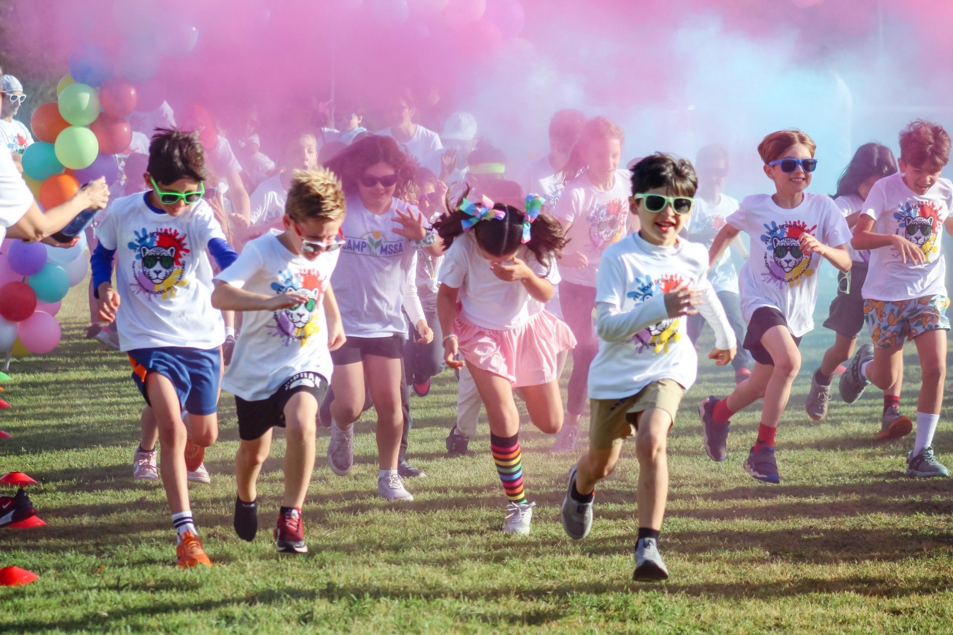 Group of elementary students running through a cloud of colored powder.