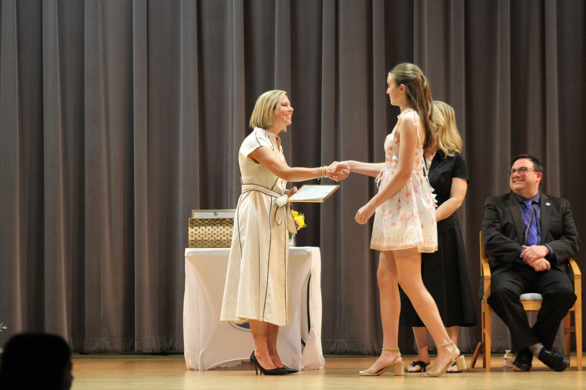 A graduate receiving her Certificat of Completion from the Head of School.