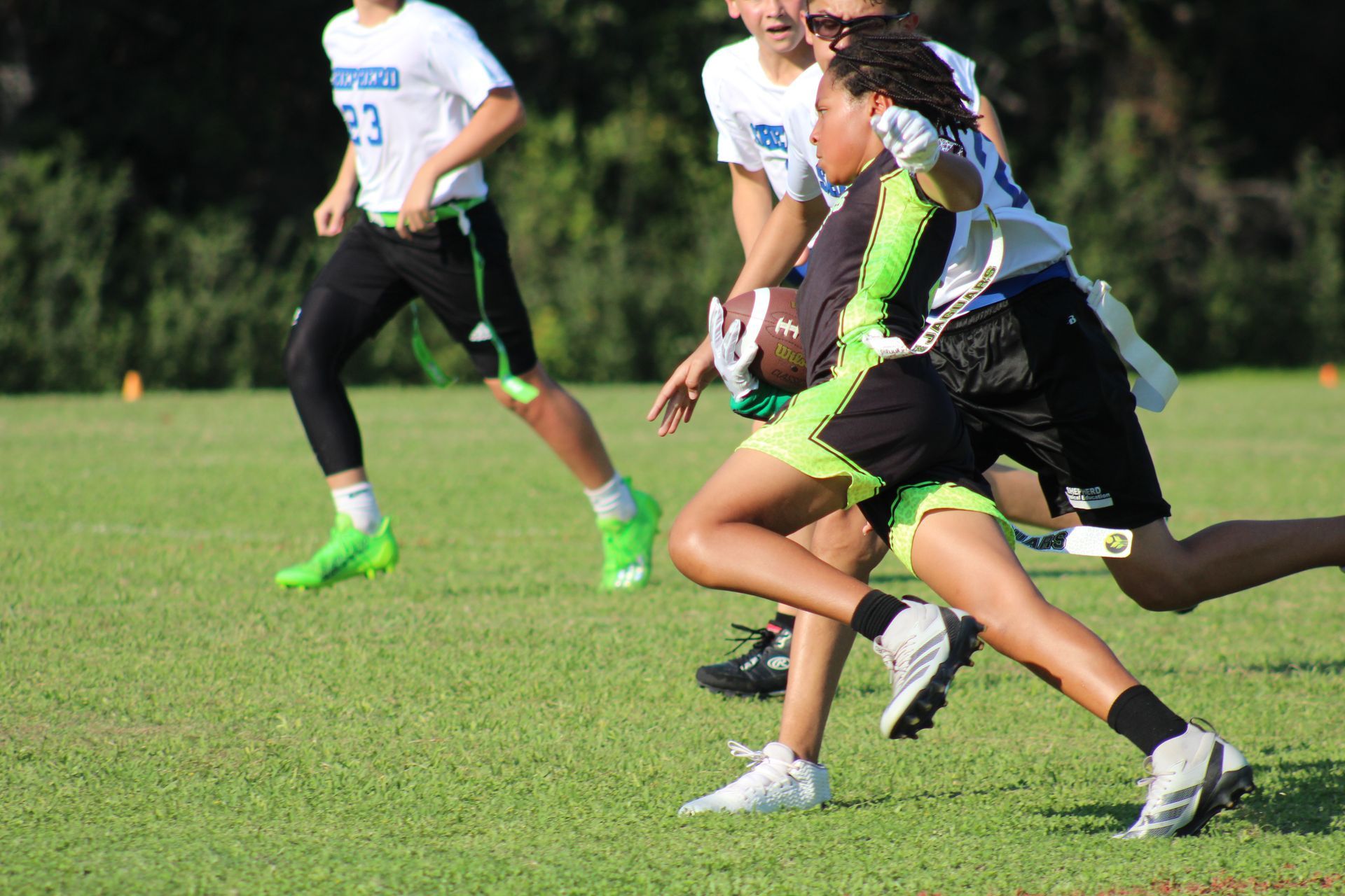 A boy holding a football runs past the opponent.