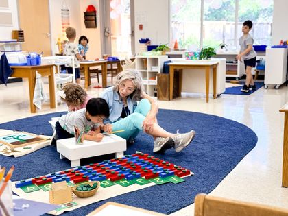 Child working with teacher on a blue rug using the number rods to build the digits 1 through 9.