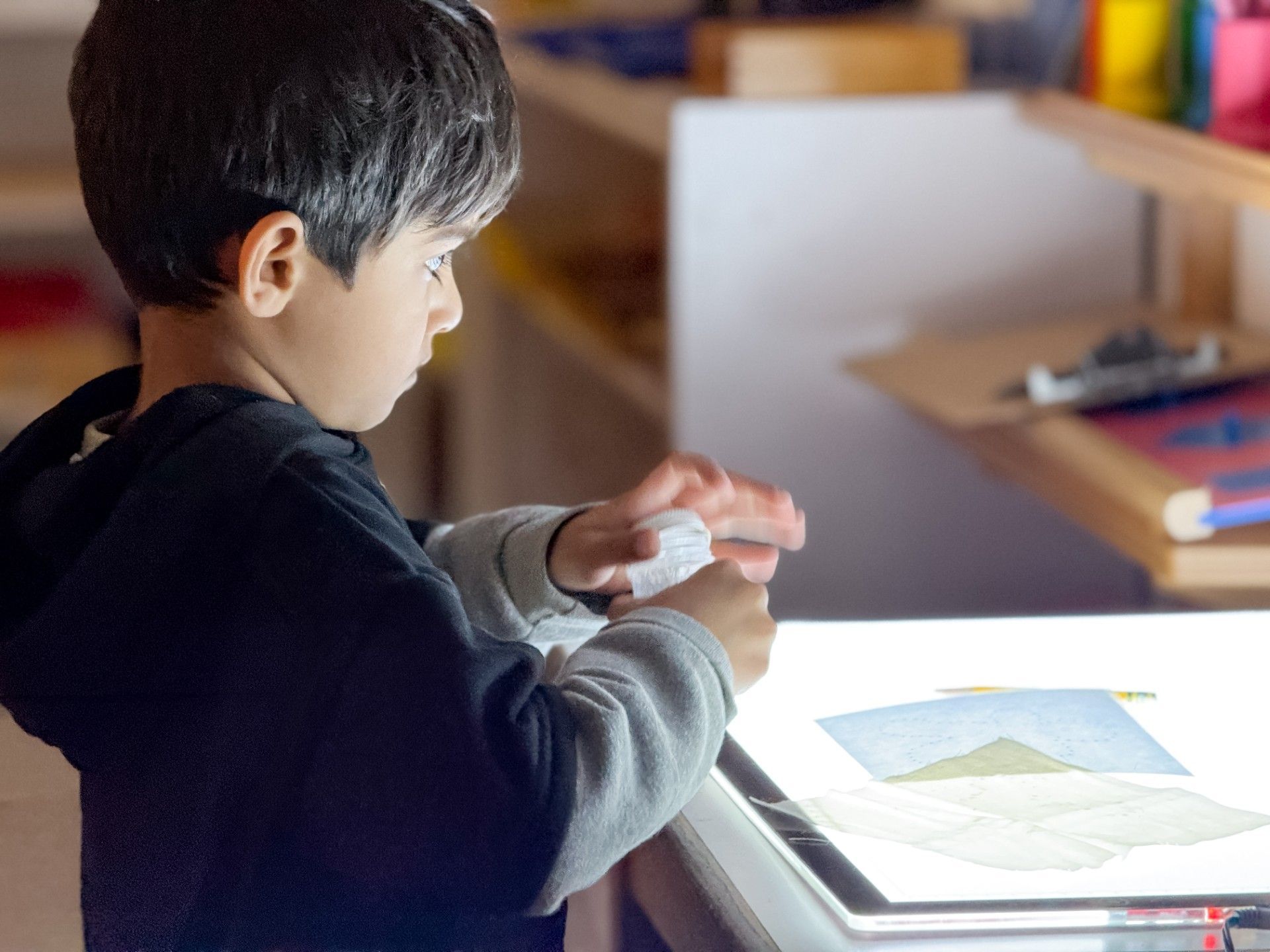 Boy using a light table to trace a drawing.