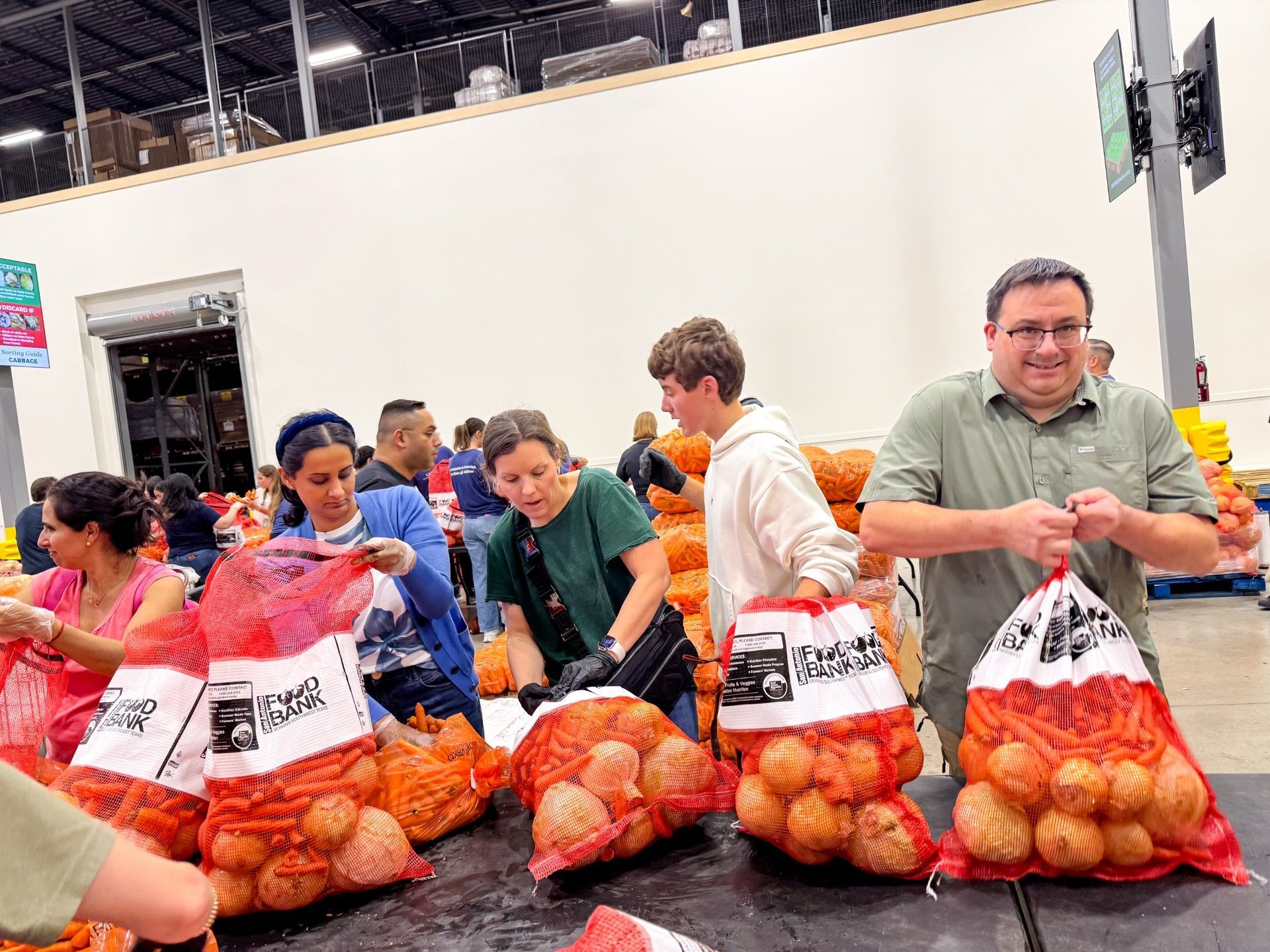 Two students and two adults bagging onions at the Food Bank.