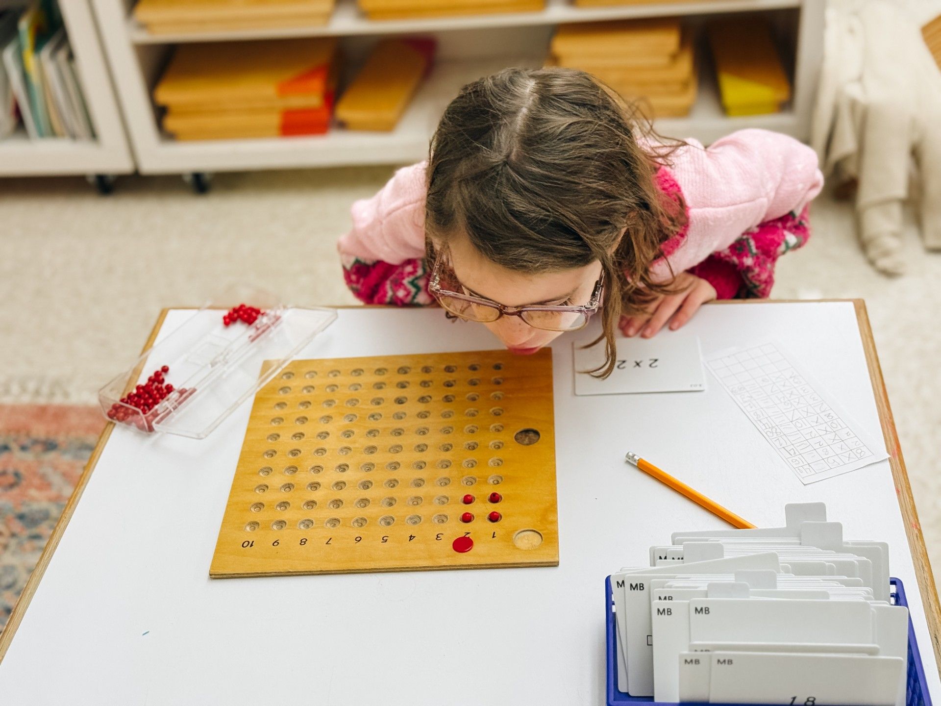 A child using beads and a peg board to map out 2 x 2.