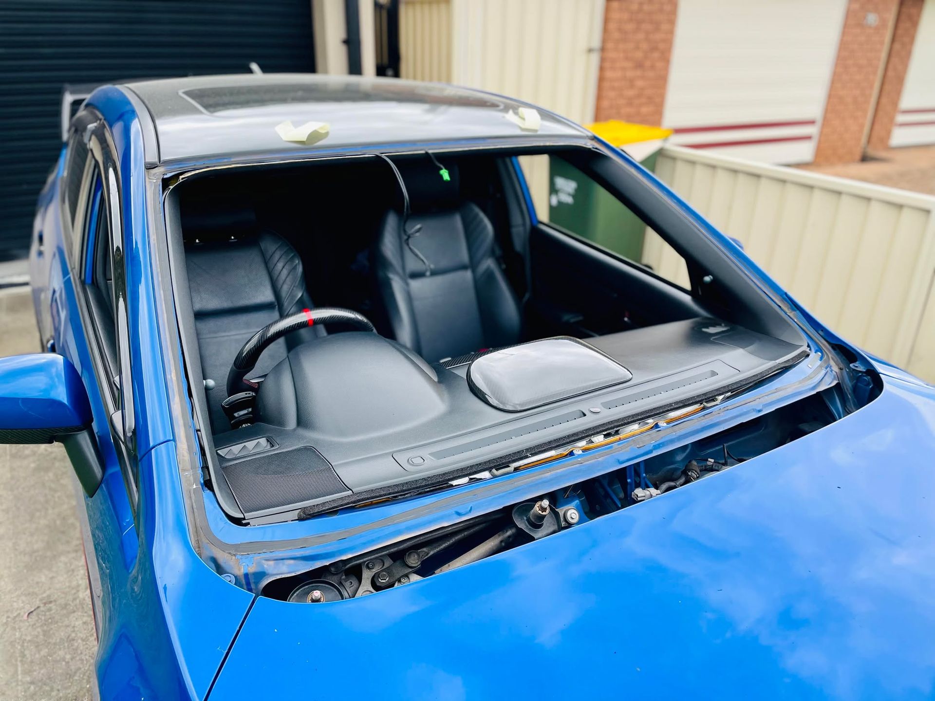 Yellow classic car with hood open, showing engine in a garage