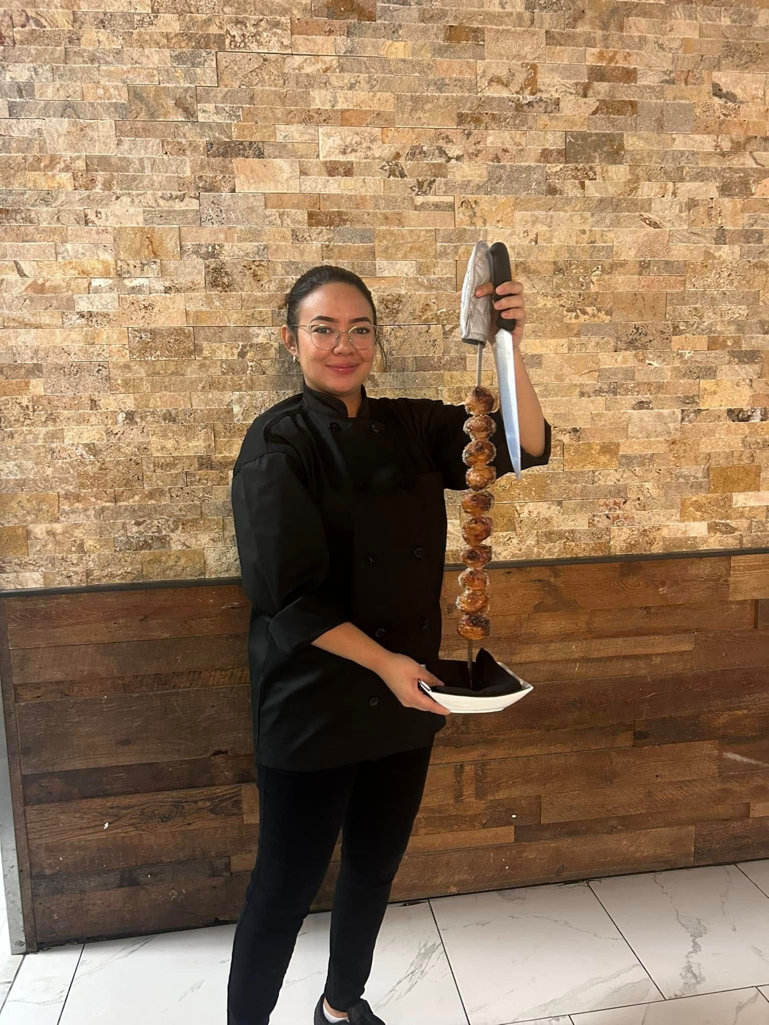woman in black outfit holding meat on a skewer