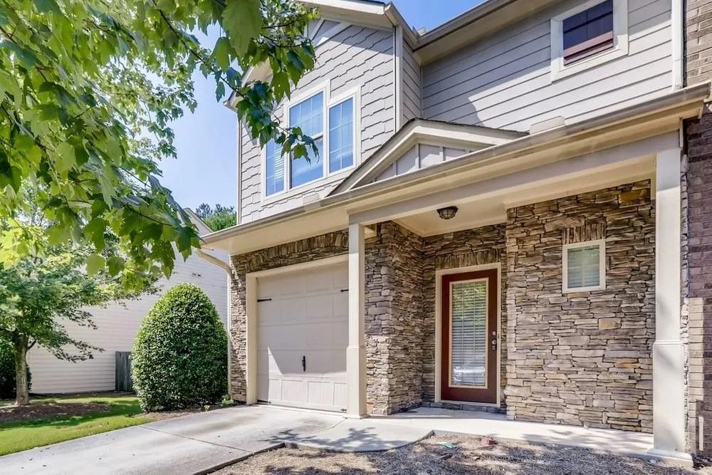 The front of a house with a stone wall and a porch.