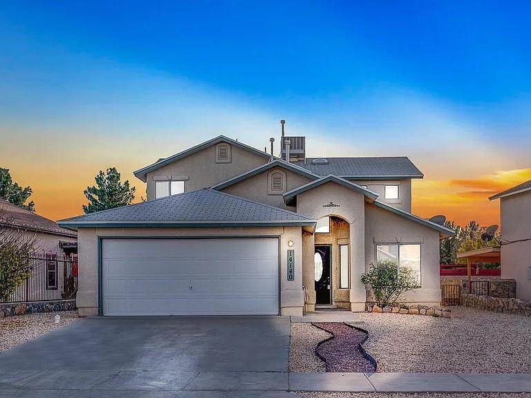 A large house with a garage and a sunset in the background
