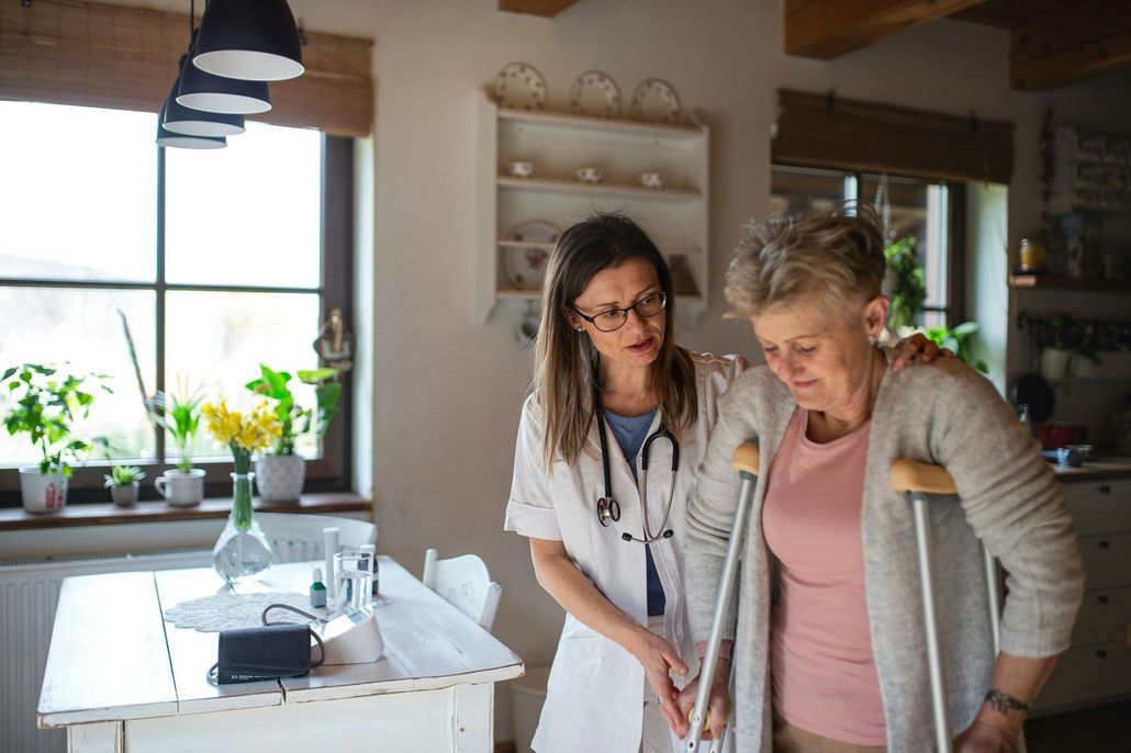 A nurse is helping an elderly woman walk with crutches.